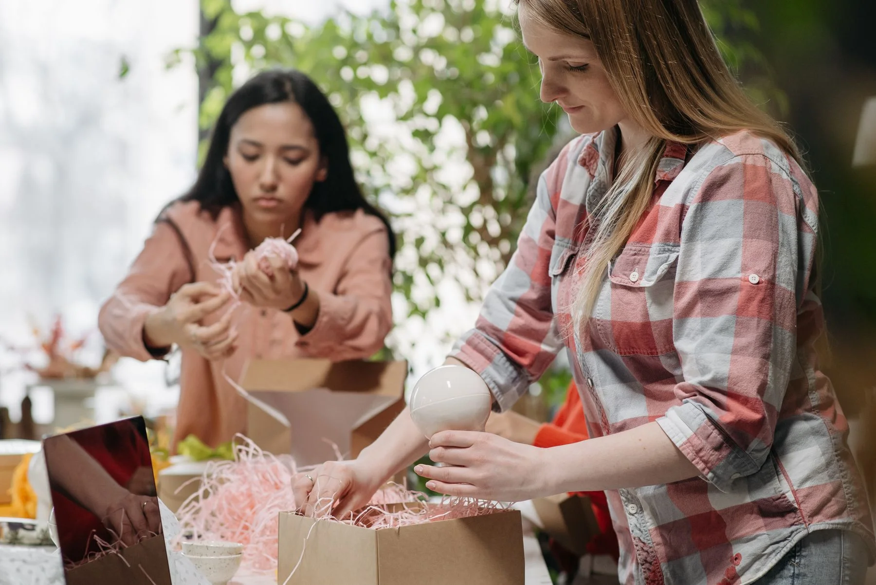 Emprendedoras preparando pedidos en cajas de cartón en su espacio de trabajo