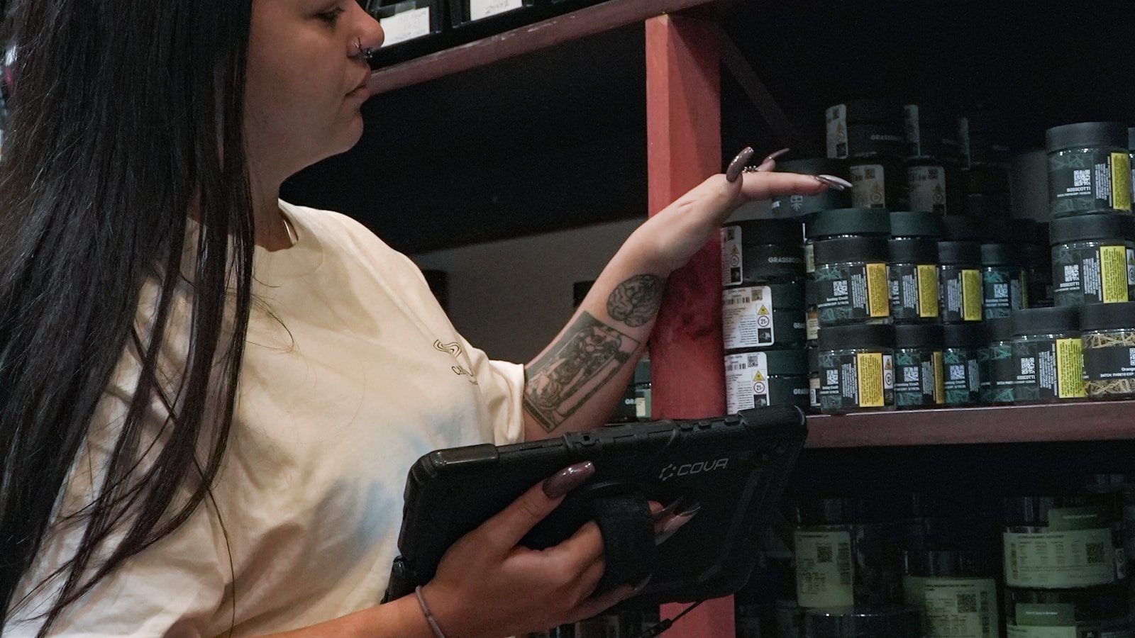 Persona controlando el inventario de productos en estanterías con una tablet