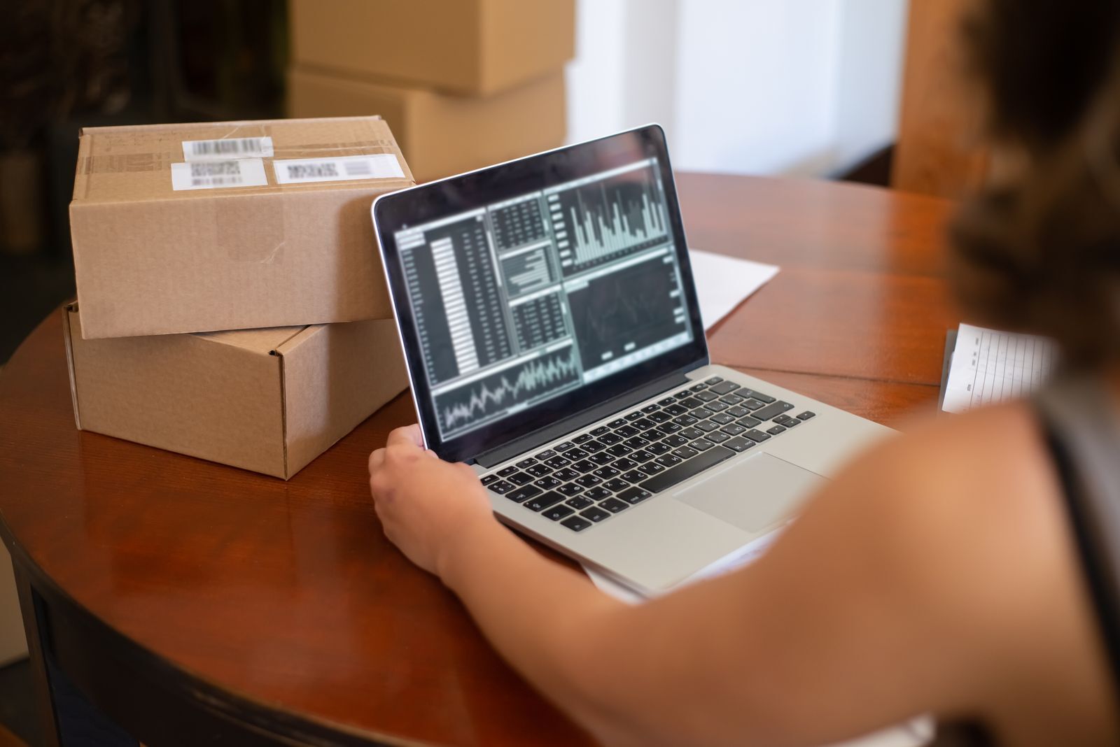Mesa de despacho con varias cajas etiquetadas junto a una notebook abierta, gestionando pedidos de distintos canales