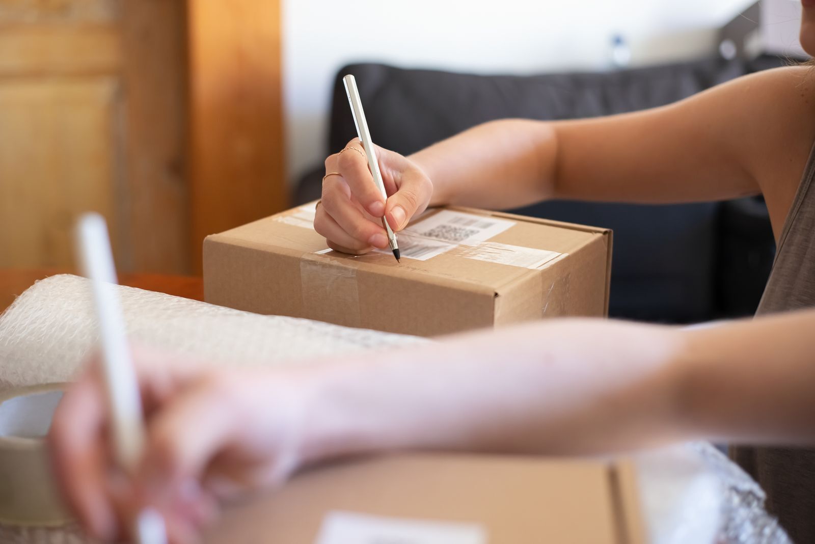 Mano escribiendo a mano los datos de envío sobre una caja de cartón